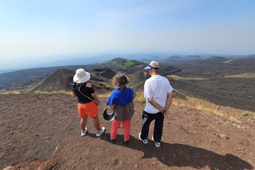 Three people standing on a rocky hill overlooking a vast landscape. 1