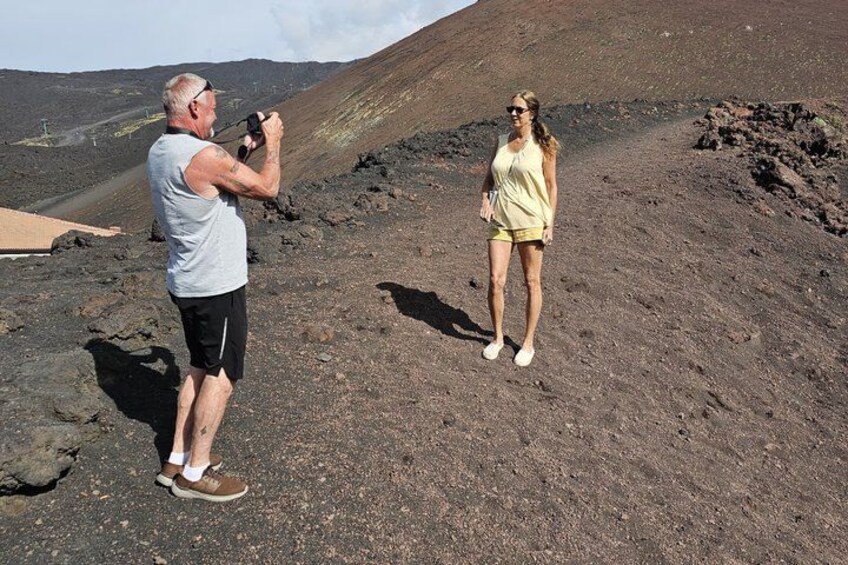Two people on a volcanic landscape, one taking a photo. 2
