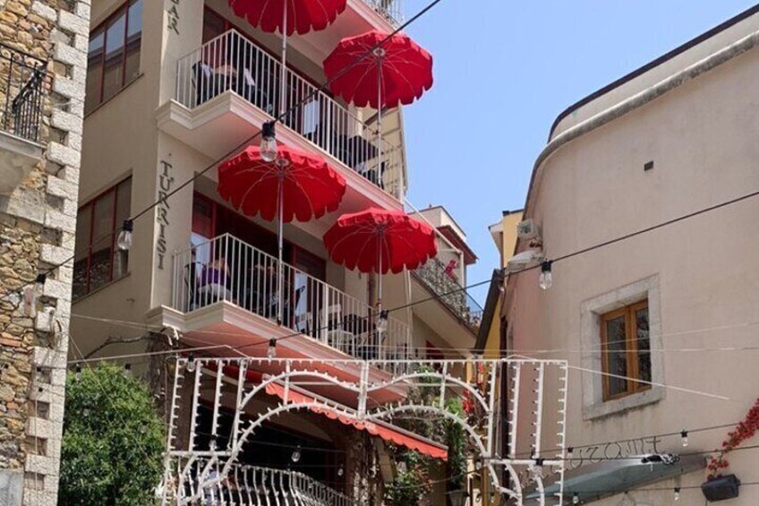 Un edificio con balcones decorados con sombrillas rojas y luces blancas. 1