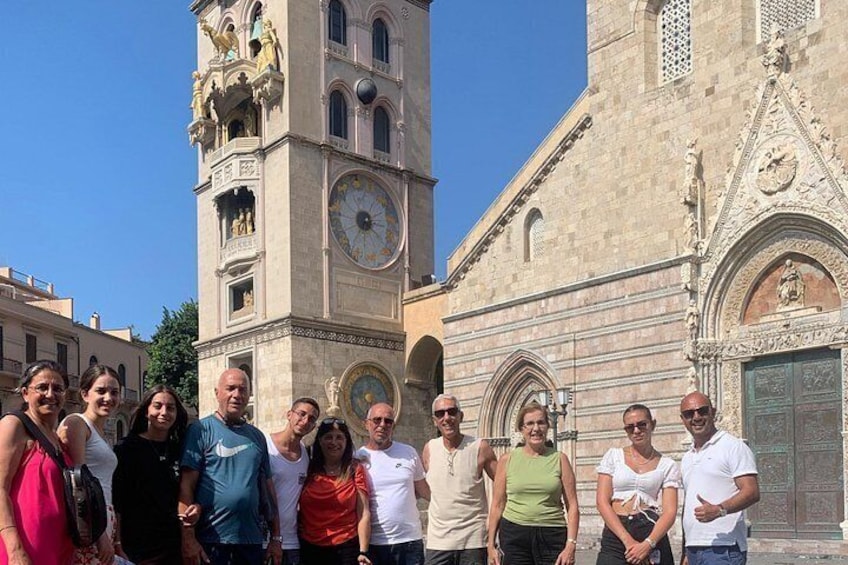 Un grupo de personas frente a un edificio histórico con una torre del reloj y arquitectura ornamentada. 3