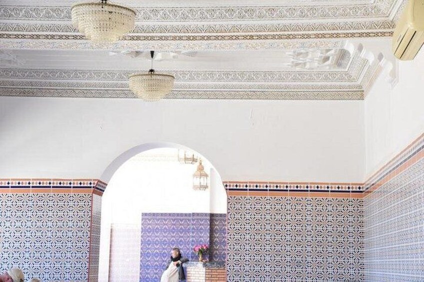 A room with intricate tile patterns, a chandelier, and a large arched doorway. 1