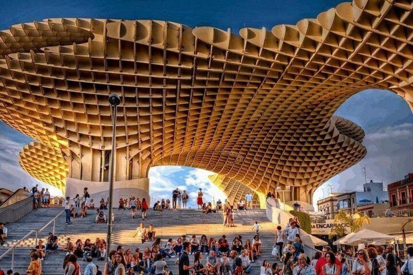 A large, modern architectural structure with a unique, wave-like roof design, surrounded by a crowd of people. 4