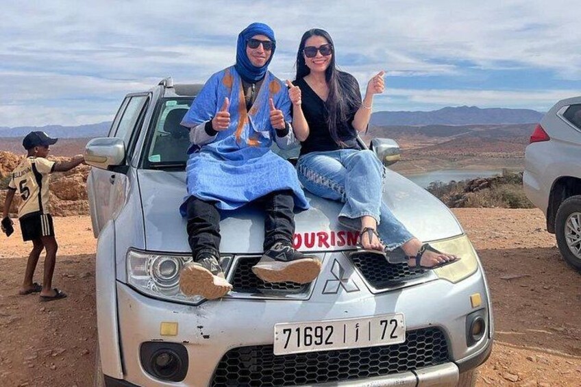 Two people sitting on a car with a desert landscape in the background. 4