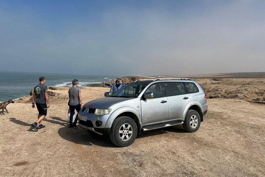 A silver SUV parked on a sandy beach with a clear sky and ocean in the background. 5