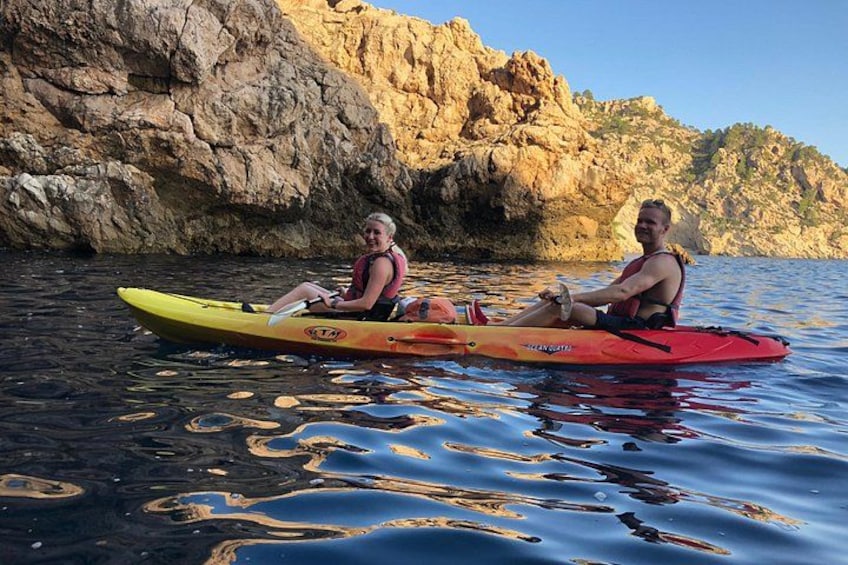 Two people kayaking on a calm body of water with rocky cliffs in the background. 5