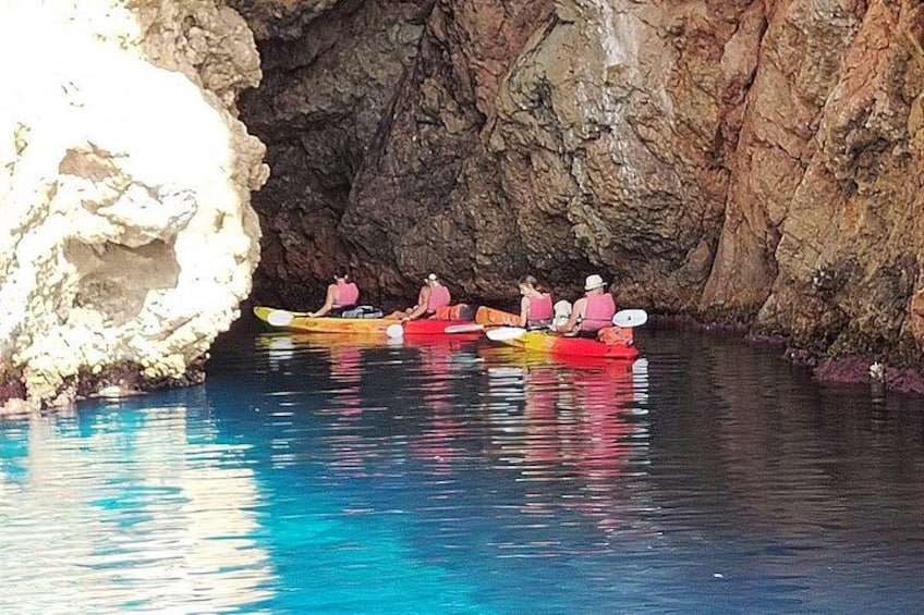 People kayaking in a cave with rocky walls and clear blue water. 2