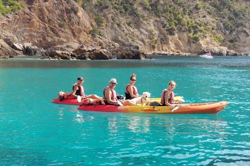 People on a red and yellow raft in turquoise water with a rocky coastline in the background. 3