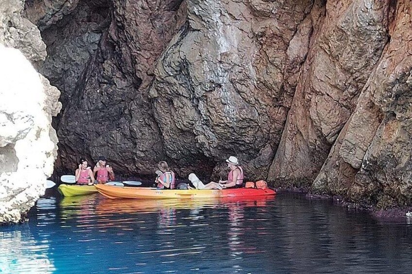 A group of people in kayaks in a rocky cave. 4