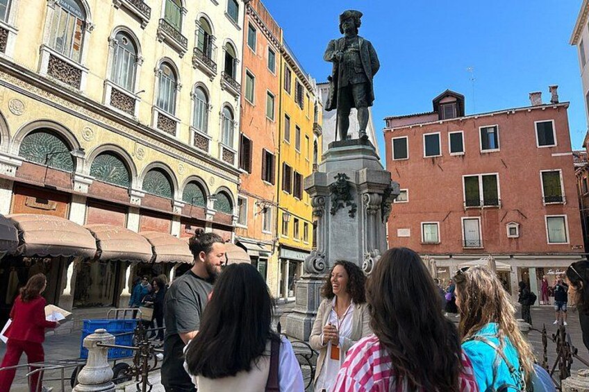 A group of people standing in front of a statue in a square with historic buildings in the background. 3