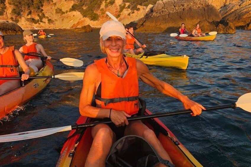 People kayaking on a calm body of water with rocky cliffs in the background. 3