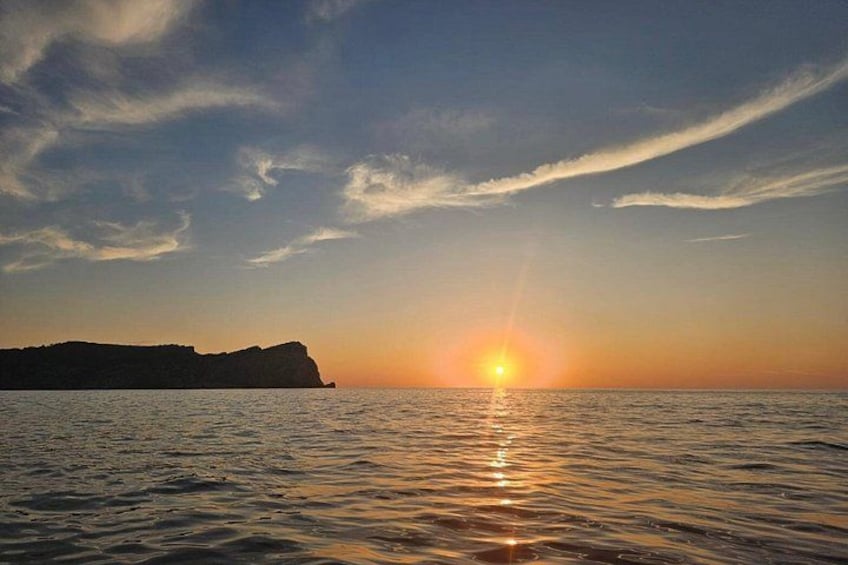 A sunset over a calm sea with a silhouette of cliffs. 5