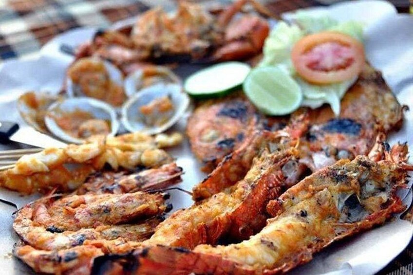 Grilled seafood, including shrimp and lobster, served with a side of vegetables and a drink. 1