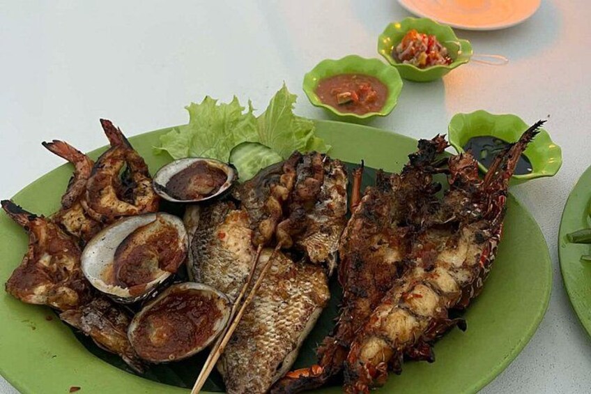 Grilled fish and clams on a green plate with side dishes. 2