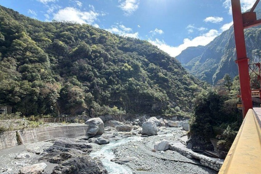 A river with large boulders, a bridge, and a mountainous landscape. 4