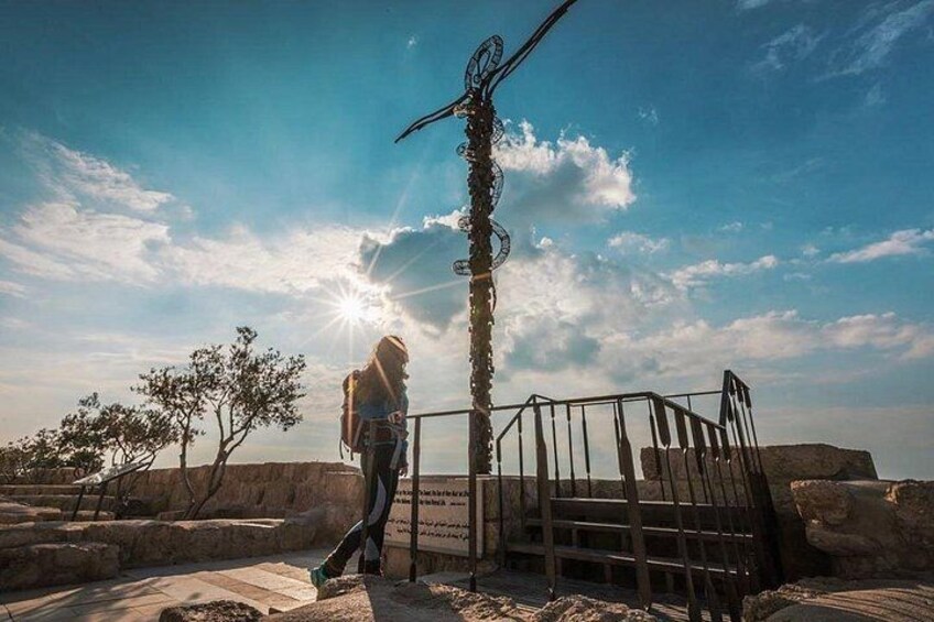 A person hiking with a backpack, a metal sculpture, and a gate in a natural landscape. 2