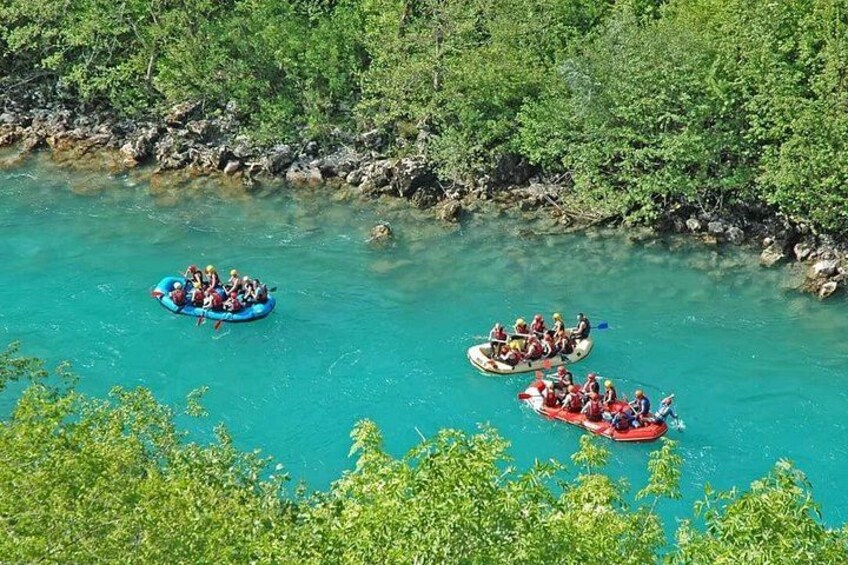 Tres grupos de personas hacen rafting en un río turquesa rodeado de vegetación. 1