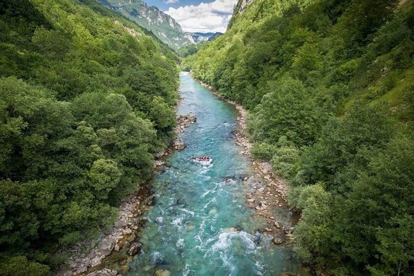 Un río serpentea por un valle boscoso, con orillas rocosas y abundante vegetación. 5