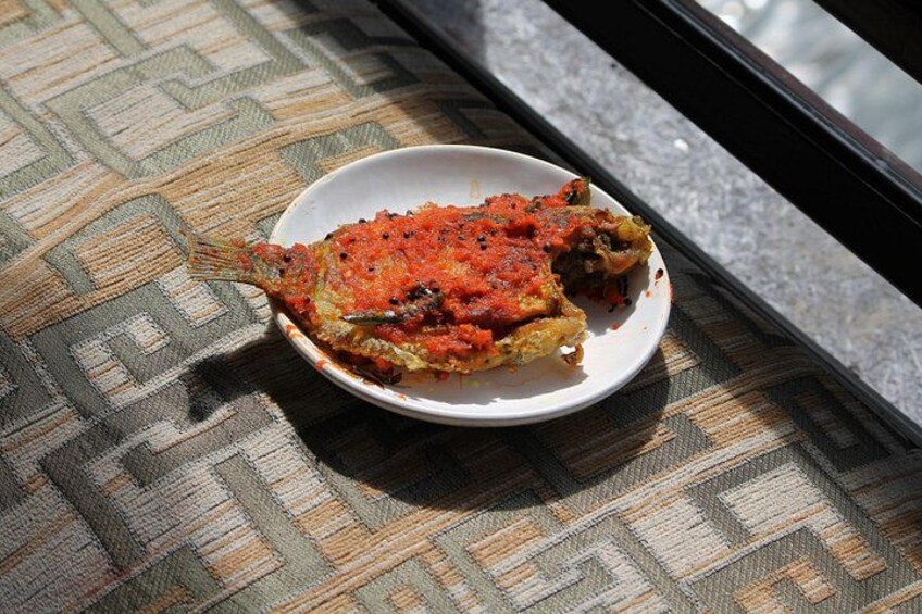 A fish dish on a plate with a patterned tablecloth. 2