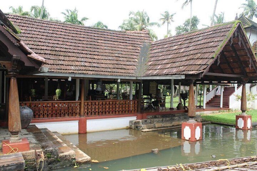 A traditional building with a tiled roof, a covered seating area, and a small pond. 4