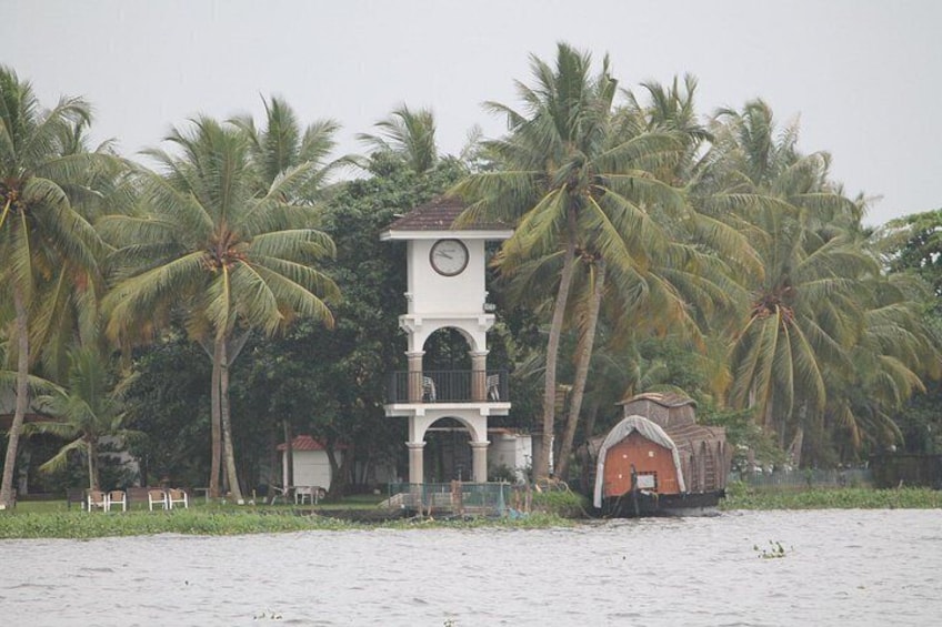 A coastal scene with a clock tower, palm trees, and a small building. 5