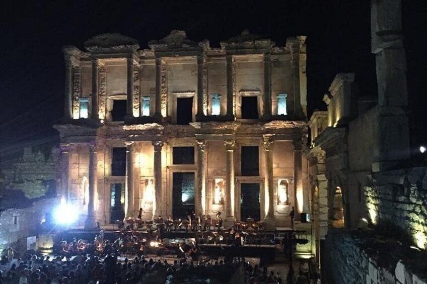 Un bâtiment ancien, doté de colonnes et d’arcades, illuminé la nuit. 3