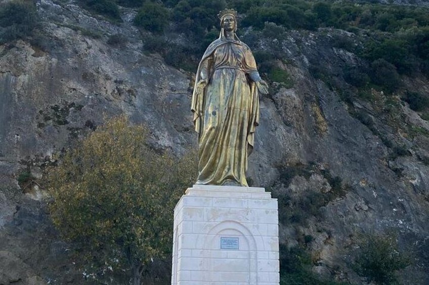 A statue on a pedestal with a rocky hillside in the background. 2