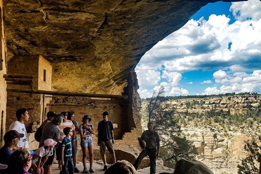 A group of people inside a cave with a view of a rocky landscape outside. 2