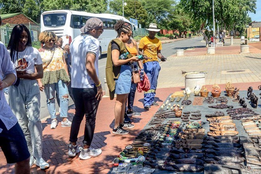 Een straatmarkt met mensen die rondkijken en diverse waren die op de grond liggen. 2