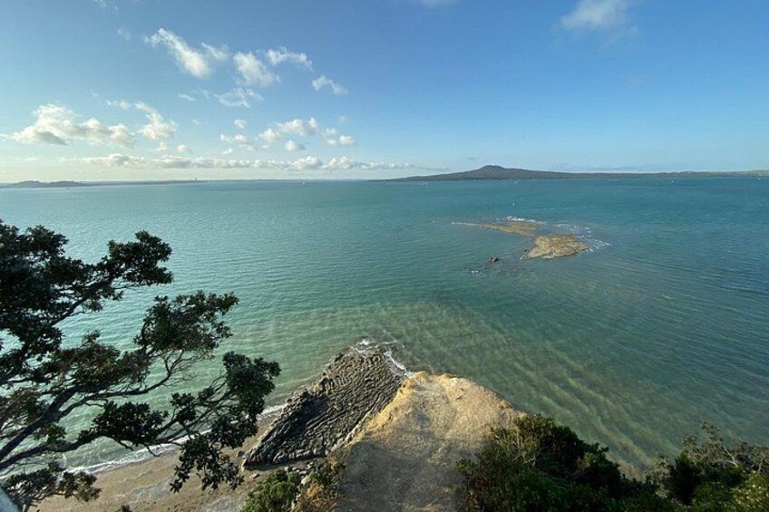 Un paysage côtier avec une eau claire, une plage de sable et une montagne à l’horizon. 1