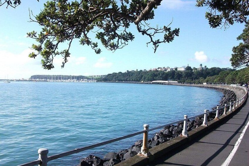 Une promenade en bord de mer dotée d’une rambarde, avec une eau d’un bleu limpide et une côte lointaine parsemée de bâtiments. 5