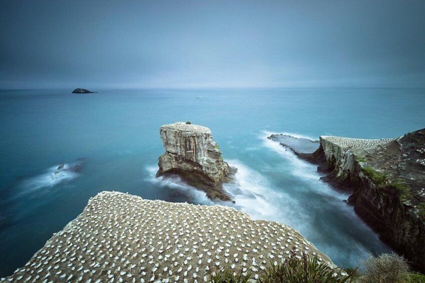 A coastal landscape with a prominent rock formation and a calm sea. 2