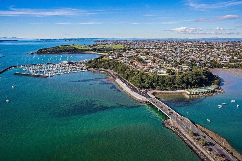 A coastal town with a marina, a bridge, and a forested island. 1
