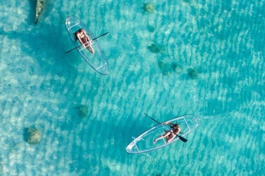 Two people paddling kayaks on a turquoise sea. 5