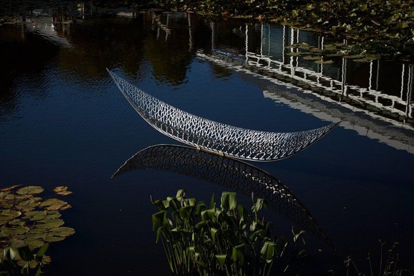 A boat on a calm body of water with lily pads and reeds. 1