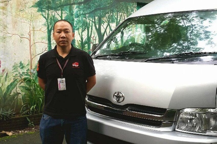 A person standing in front of a white vehicle with a logo on the front grille. 5