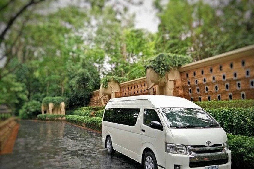 A white van parked on a wet road with a brick wall and greenery in the background. 3