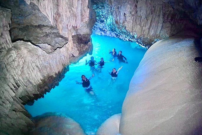 A group of people swimming in a natural pool surrounded by rock formations. 4
