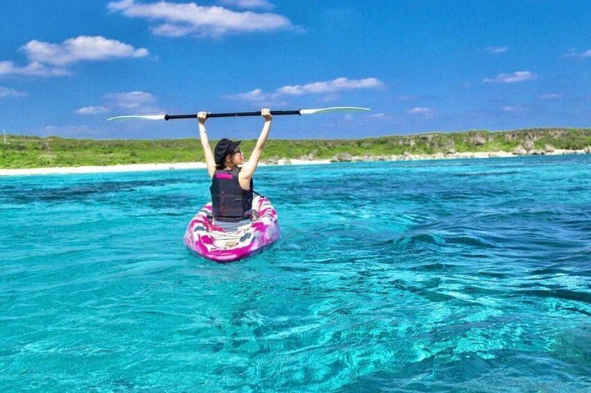 A person on a floating ring in turquoise water, holding a paddle. 2