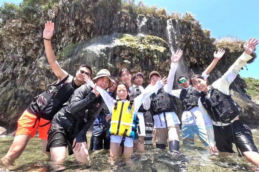 A group of people in a rocky outdoor setting, some wearing life jackets. 2