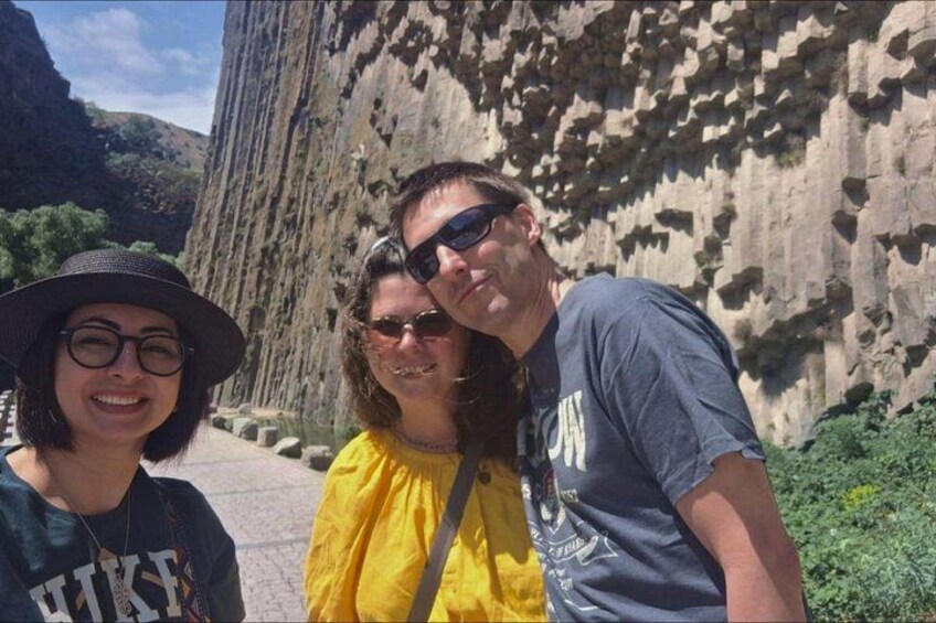 Three people standing in front of a large rock formation. 5