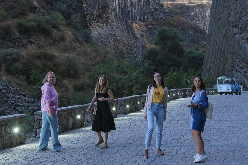 Four people walking on a paved path with a mountainous landscape in the background. 2