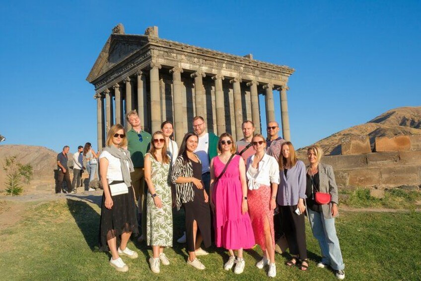 A group of people standing in front of an ancient Greek temple with columns. 1