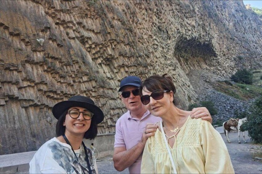 A rocky cliff with a person in a pink shirt and a hat, and another in a yellow blouse. 5