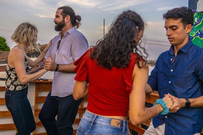 A group of people standing on a wooden deck, holding hands in a circle. 1