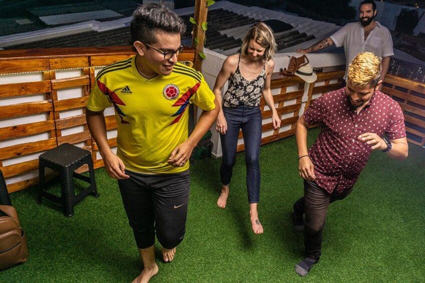 A person in a yellow sports jersey walking on artificial grass, another in a polka dot shirt, and a third person in a floral top and jeans. 2