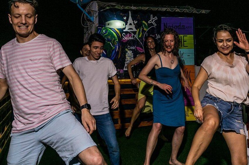 A group of people dancing in a dimly lit indoor setting with graffiti on the walls. 4