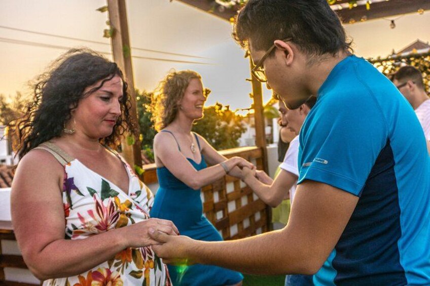 People at an outdoor event, possibly a wedding or party, with a wooden pergola and greenery in the background. 3