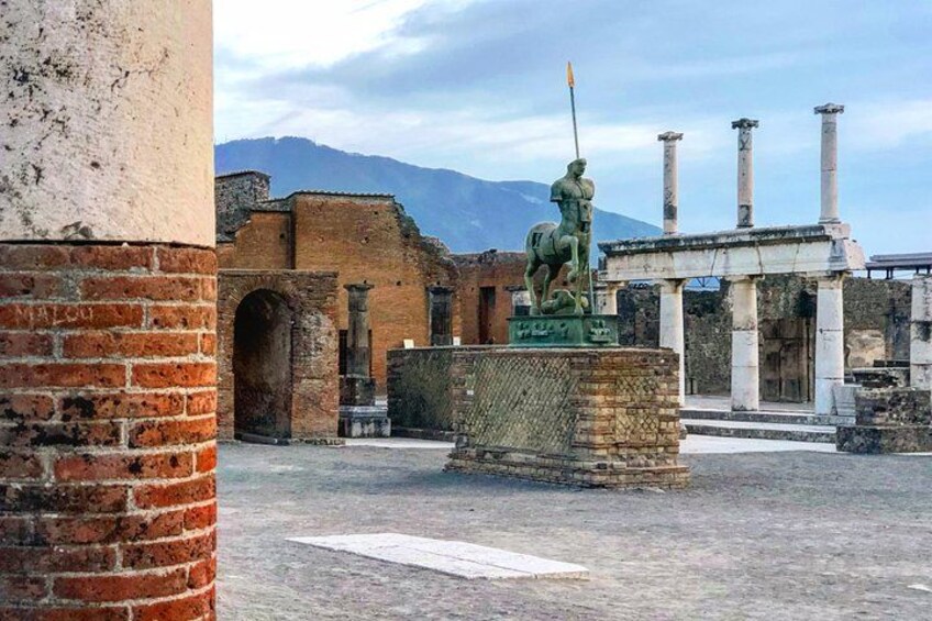 Ancient ruins with columns, a statue, and a mountain in the background. 4