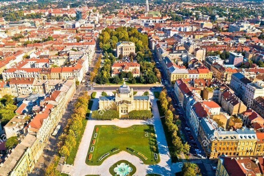 An aerial view of a city with a prominent square, historic buildings, and a large fountain. 1