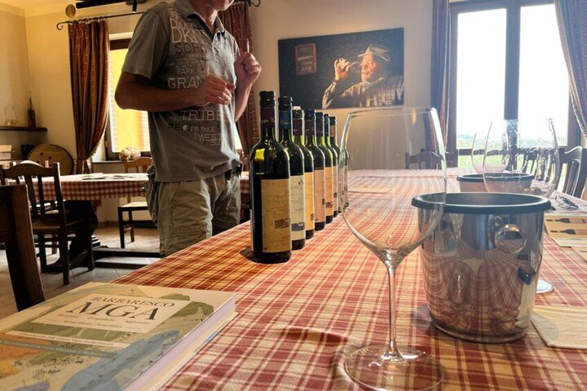 A man standing at a table with wine bottles and a glass. 2